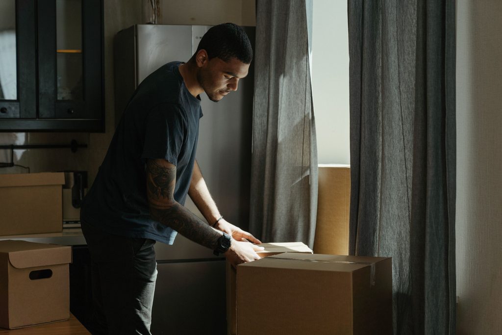 単身赴任先の部屋で引越しの段ボールを開ける男性