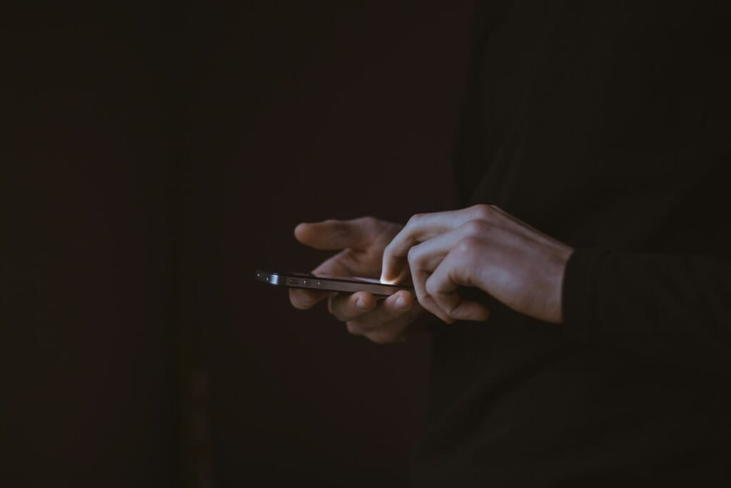 Hands using a smartphone in the dark