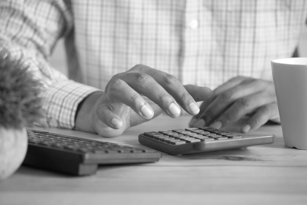 A hand using a calculator on a desk